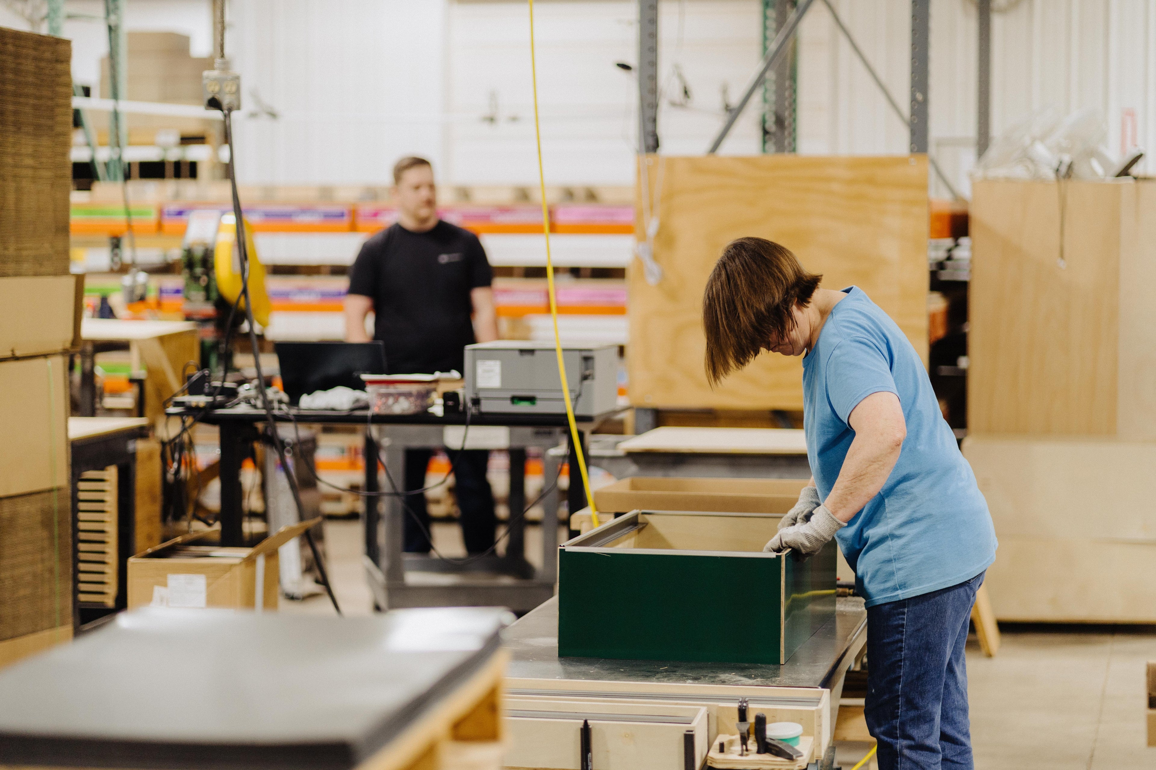 Person working in a warehouse with boxes and equipment in the background