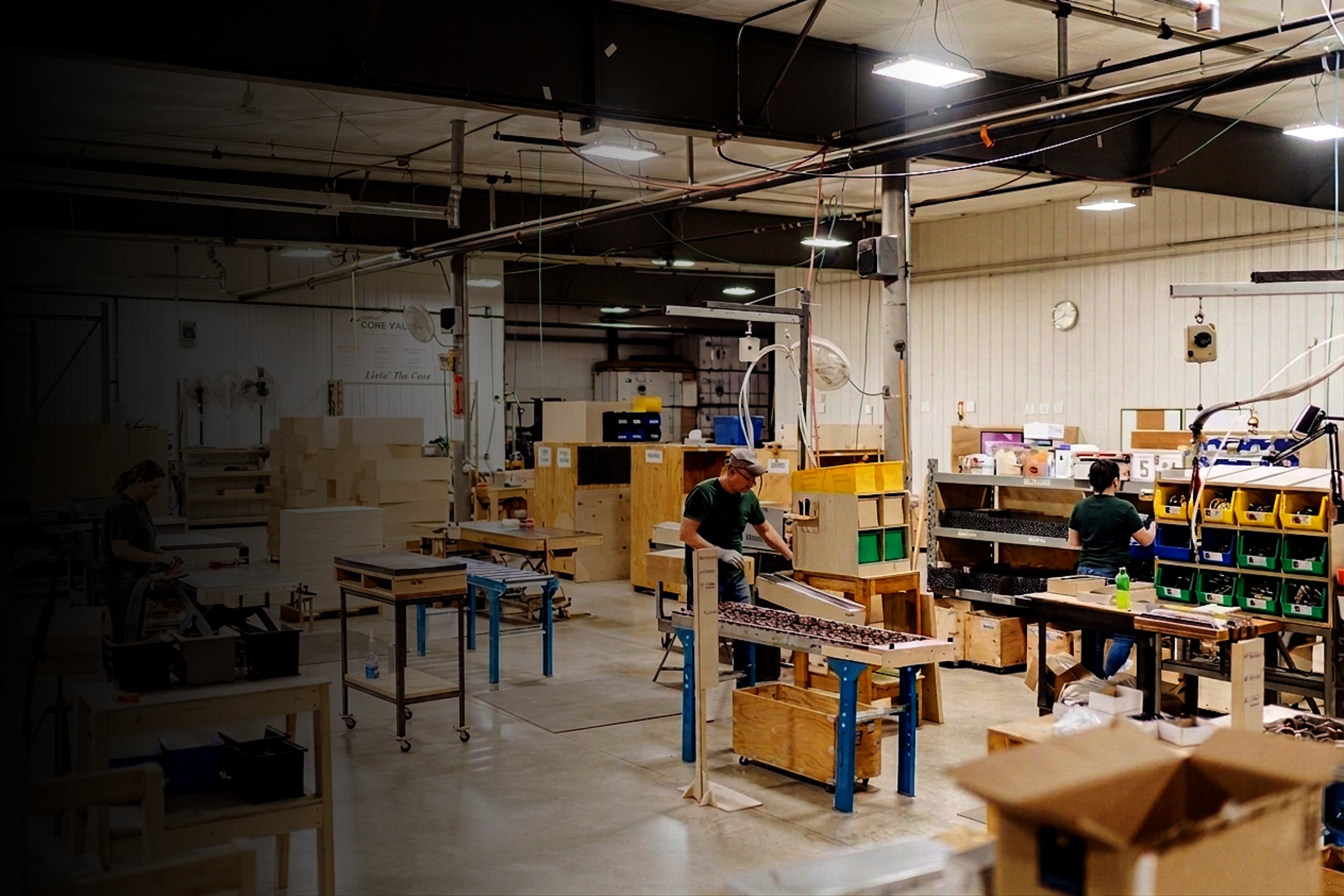 Indoors warehouse with people working on tasks, surrounded by boxes and equipment.
