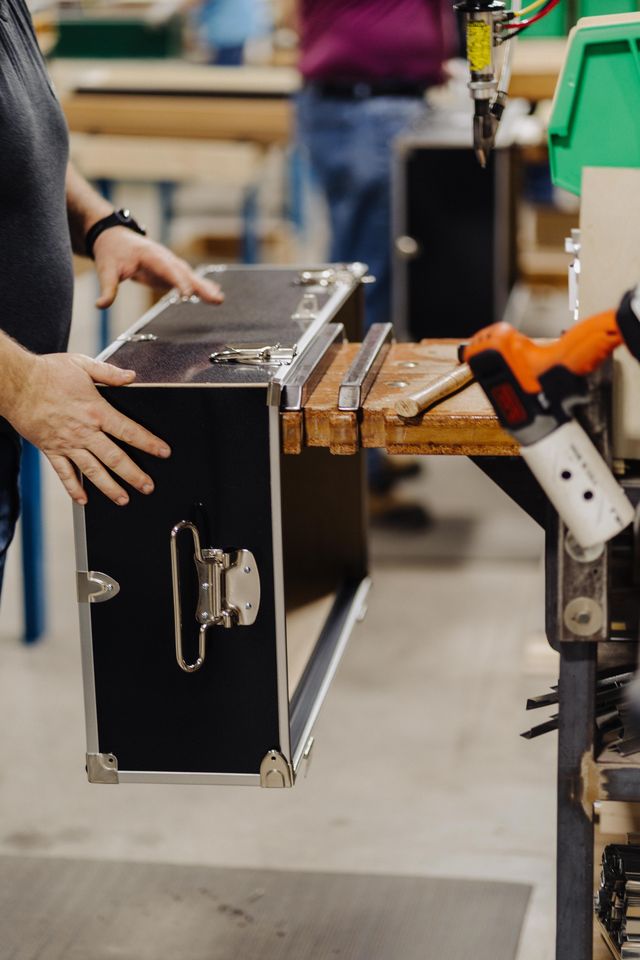 Person handling a black metal case in an industrial setting
