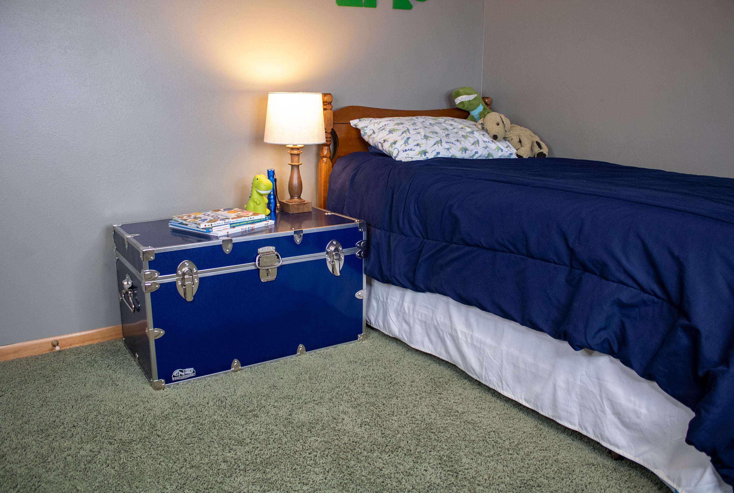 Bedroom with a blue trunk on the floor next to a bed with blue bedding.