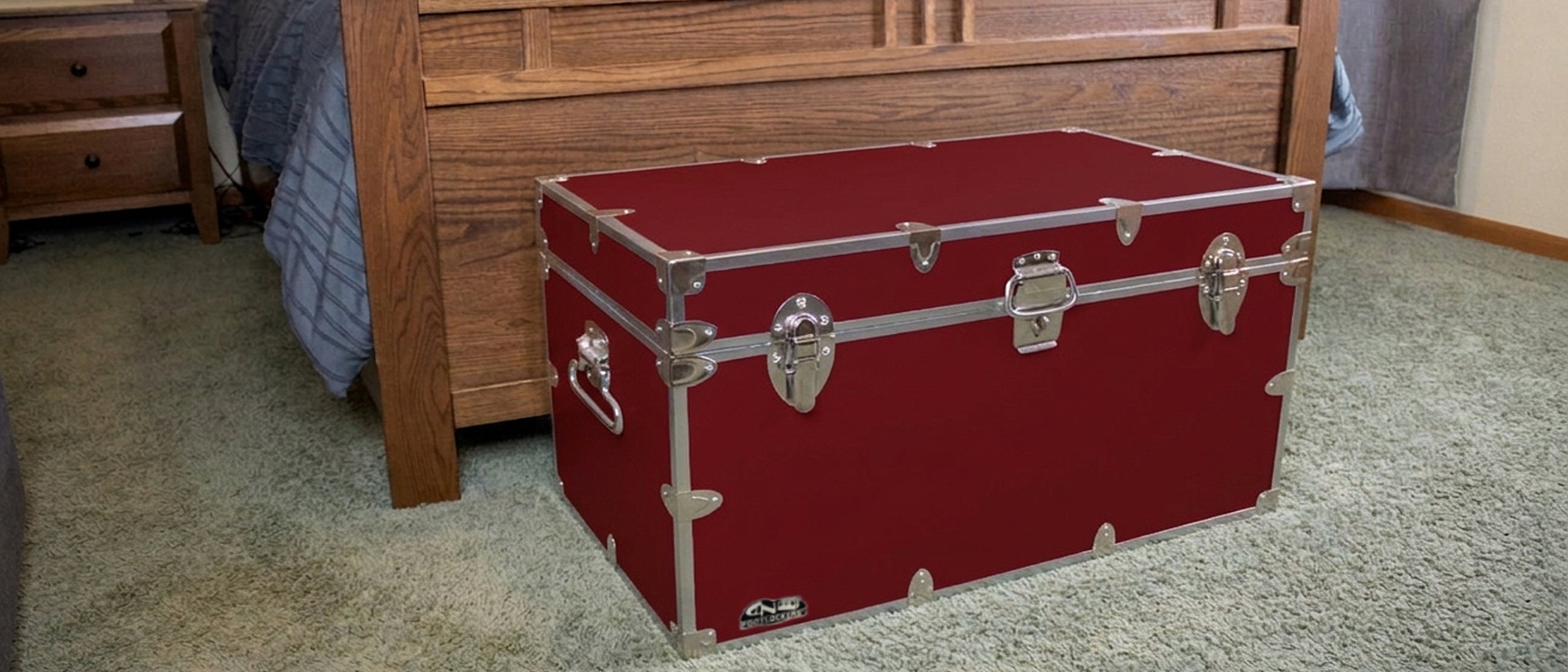 Red vintage-style trunk on a carpeted floor with wooden furniture in the background