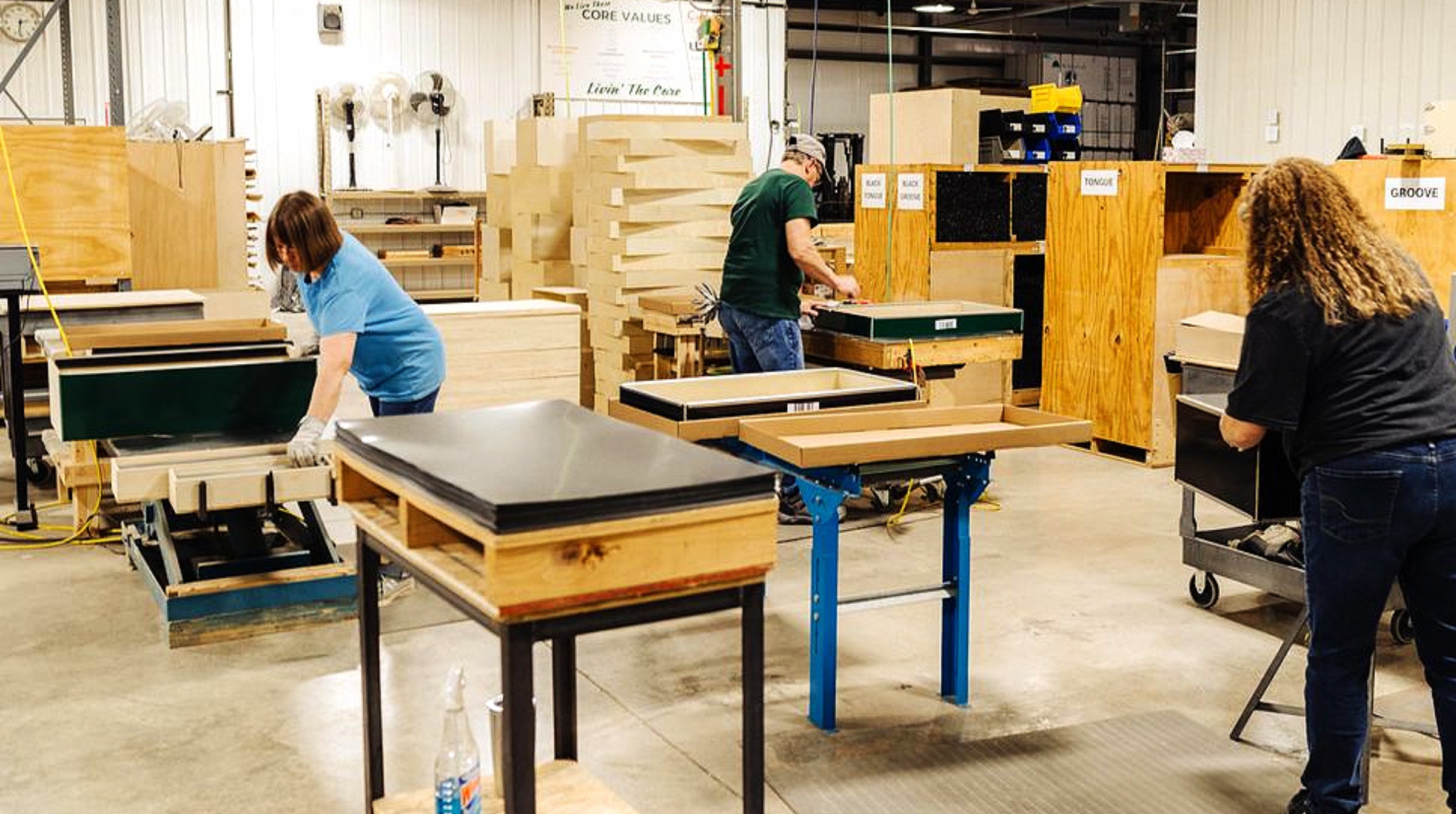 People working with wooden furniture in a warehouse setting